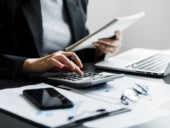 Close up of businesswomen or accountant using calculator calculate while working analytic business report on the workplace.