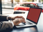 Man working on laptop on background of red car.