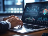 Businessman using a laptop with various graphs and charts on display.